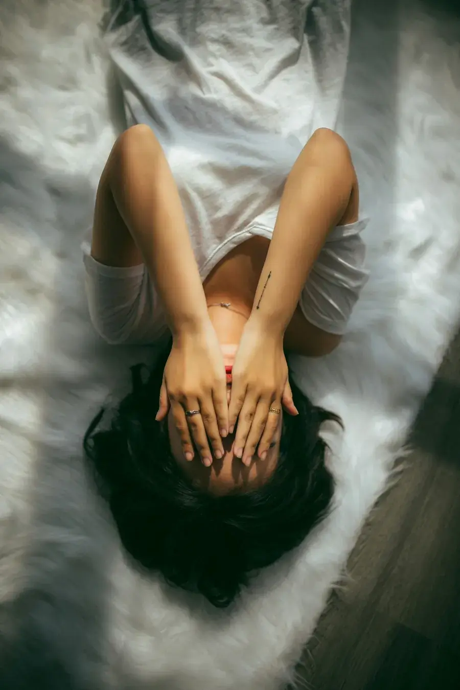 Donna distesa con le mani sul viso, immagine di stress e affaticamento
