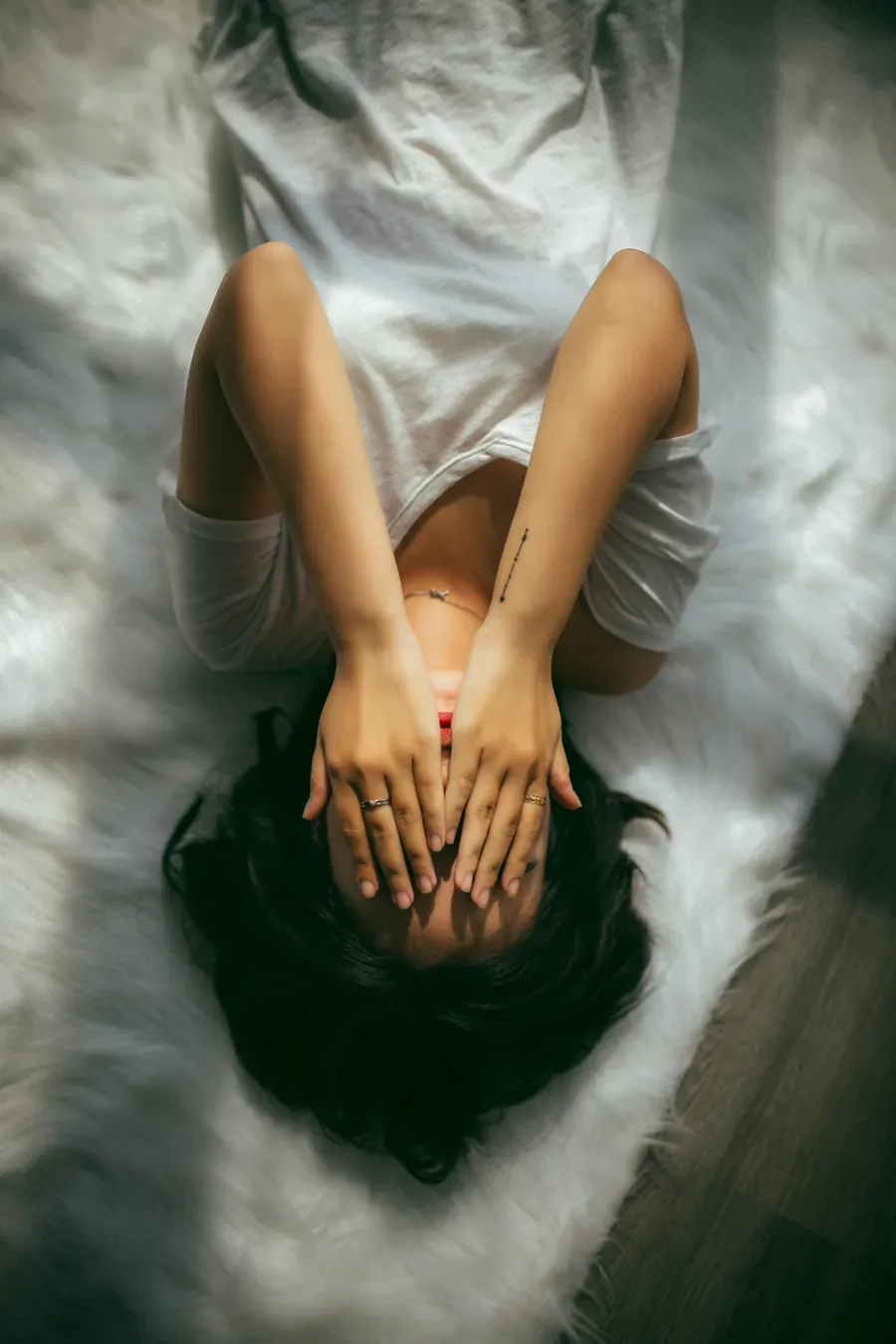 Donna distesa con le mani sul viso, immagine di stress e affaticamento